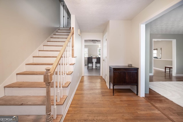 stairway with wood-type flooring and a textured ceiling