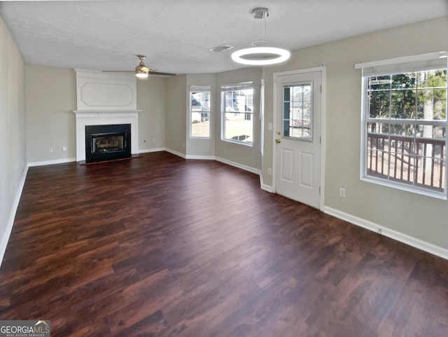 unfurnished living room with dark hardwood / wood-style flooring, ceiling fan, and a fireplace