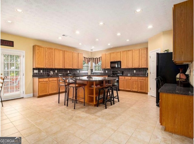 kitchen with a kitchen breakfast bar, a center island, stainless steel range oven, and light tile patterned flooring