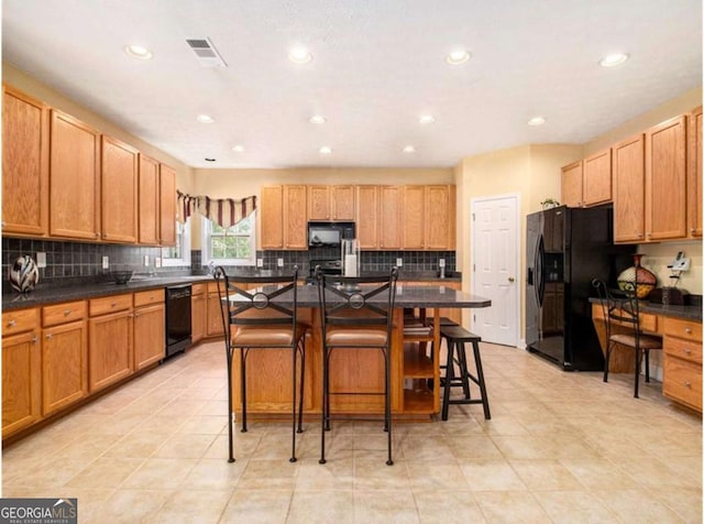 kitchen with a kitchen bar, decorative backsplash, a kitchen island, and black appliances