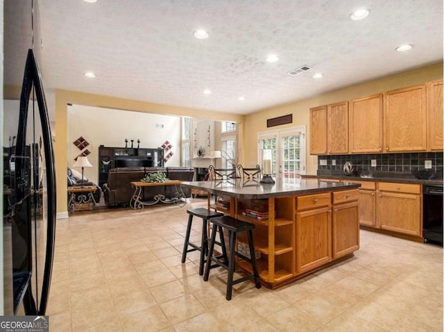 kitchen featuring decorative backsplash, french doors, black appliances, a kitchen island, and a breakfast bar area