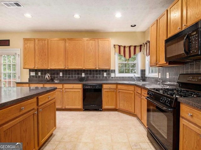 kitchen featuring light tile patterned floors, sink, plenty of natural light, and black appliances