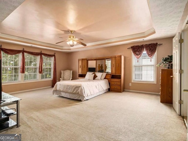 bedroom featuring a tray ceiling, ceiling fan, carpet floors, and a textured ceiling