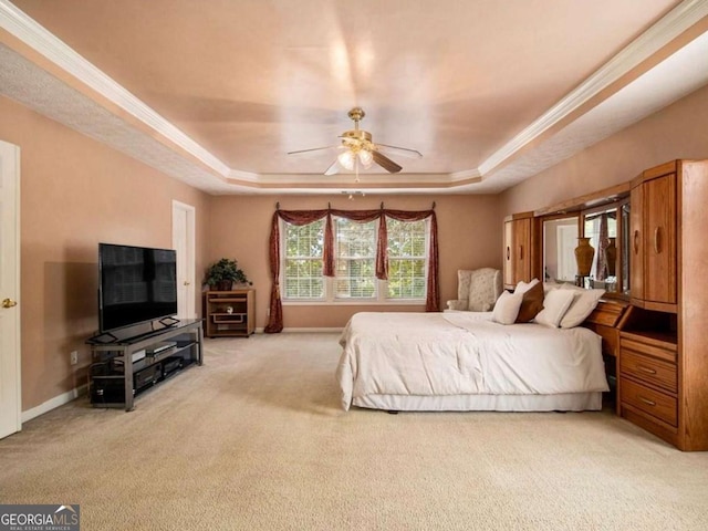 carpeted bedroom with a tray ceiling, ceiling fan, and ornamental molding