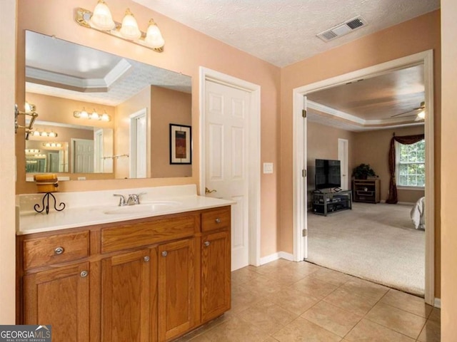 bathroom with vanity, a textured ceiling, a raised ceiling, and ceiling fan