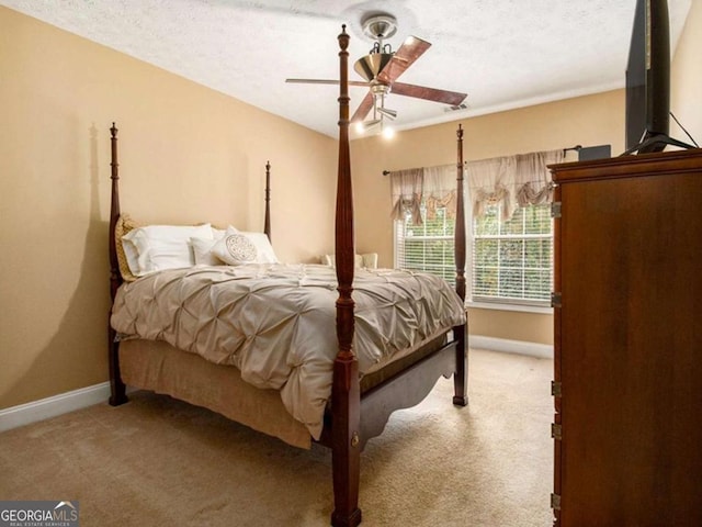 bedroom with ceiling fan, carpet, and a textured ceiling