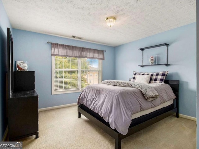 bedroom with a textured ceiling and light colored carpet