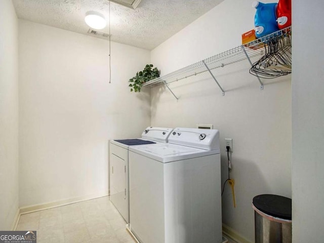 laundry area with a textured ceiling and washing machine and dryer