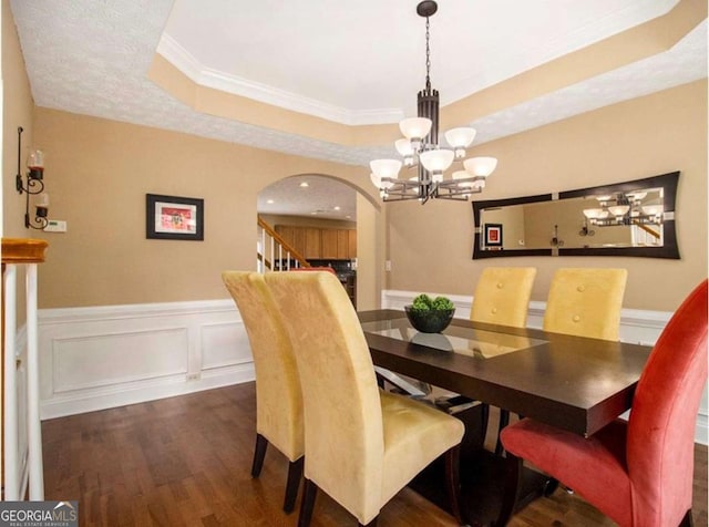 dining area featuring a tray ceiling, crown molding, dark hardwood / wood-style flooring, and a notable chandelier