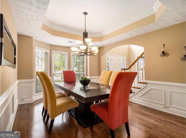 dining area featuring a tray ceiling, an inviting chandelier, dark hardwood / wood-style floors, and ornamental molding