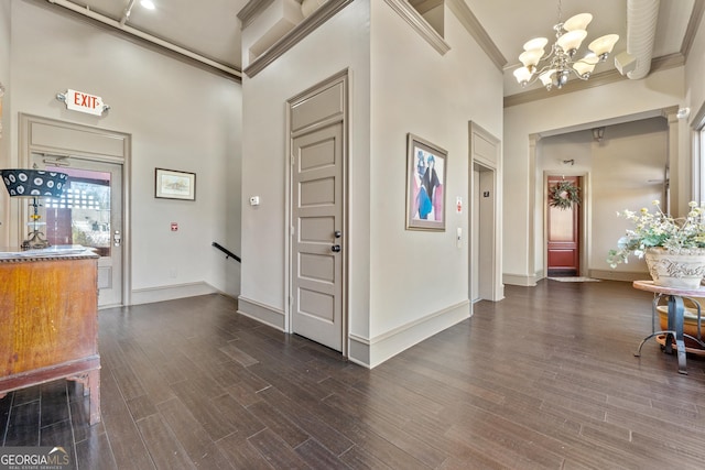 foyer featuring crown molding, dark wood-type flooring, a notable chandelier, and a towering ceiling