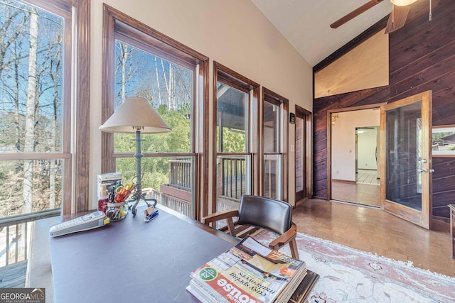 office area with wood walls, high vaulted ceiling, parquet floors, and a healthy amount of sunlight