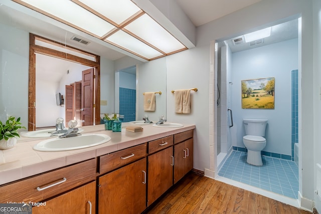 bathroom with toilet, wood-type flooring, a skylight, a shower, and vanity