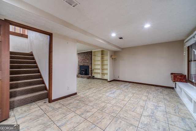 unfurnished living room with built in shelves, a brick fireplace, and a textured ceiling