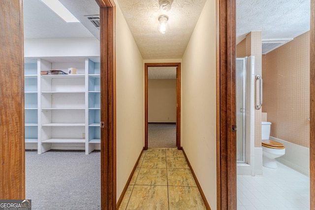 hallway featuring light carpet and a textured ceiling