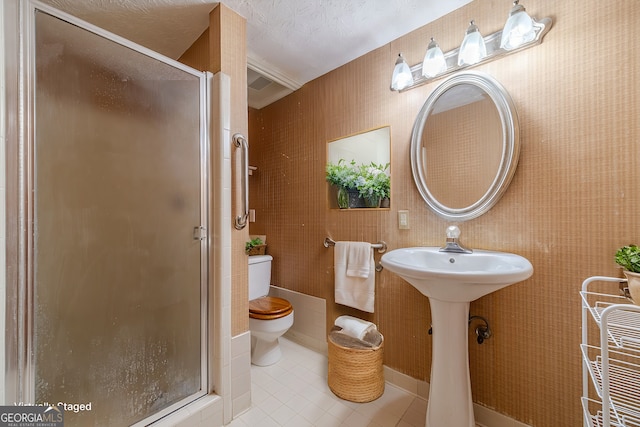 bathroom with toilet, a textured ceiling, a shower with shower door, and tile patterned floors