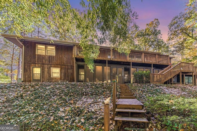 back house at dusk featuring a wooden deck