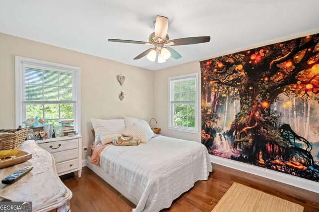 bedroom with multiple windows, ceiling fan, and dark hardwood / wood-style flooring