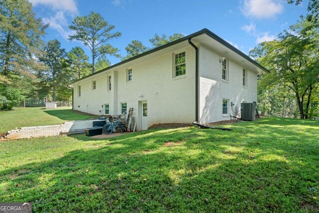 rear view of house featuring a lawn and central AC unit