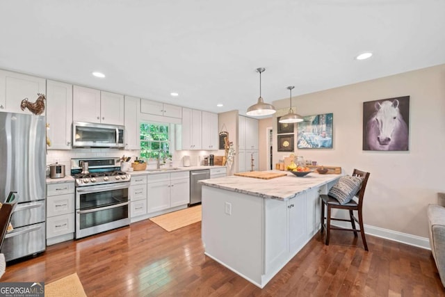 kitchen featuring white cabinetry, stainless steel appliances, backsplash, kitchen peninsula, and decorative light fixtures