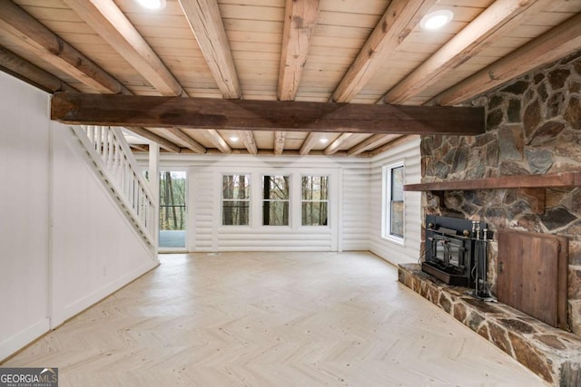 unfurnished living room with beam ceiling, a wood stove, and light parquet flooring