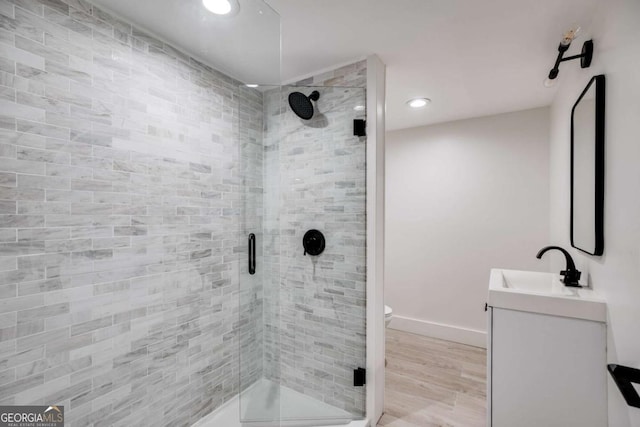 bathroom featuring vanity, hardwood / wood-style flooring, toilet, and a shower with shower door