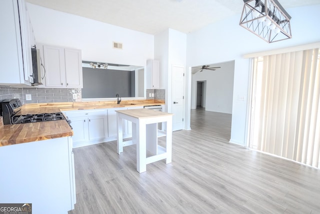 kitchen with tasteful backsplash, white cabinetry, and butcher block counters