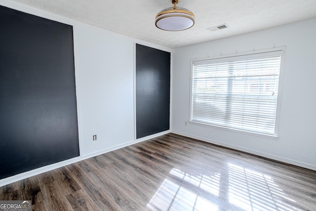 unfurnished room featuring wood-type flooring and a textured ceiling