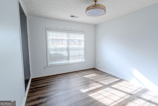 empty room with hardwood / wood-style floors and a textured ceiling