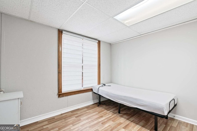 bedroom with a paneled ceiling and light wood-type flooring