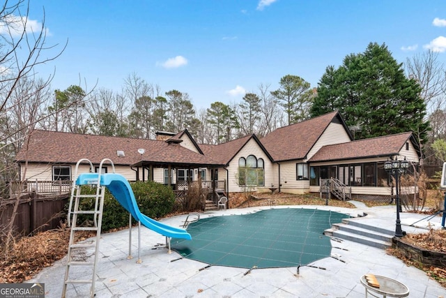 view of pool with a sunroom, a water slide, and a patio