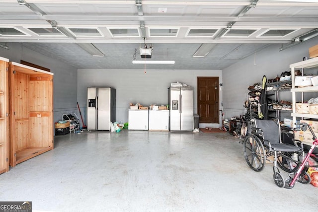 garage with stainless steel refrigerator with ice dispenser, a garage door opener, washer and clothes dryer, and fridge with ice dispenser