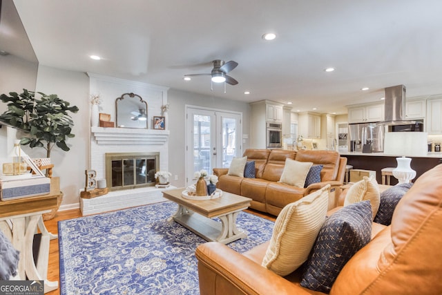 living room with light hardwood / wood-style floors, a brick fireplace, and ceiling fan