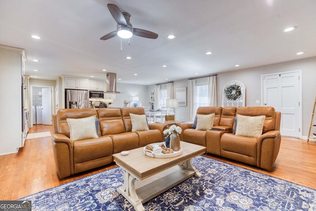 living room with washer / clothes dryer, ceiling fan, and light hardwood / wood-style floors