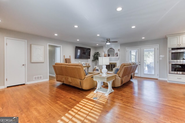 living room featuring french doors, light hardwood / wood-style floors, and ceiling fan