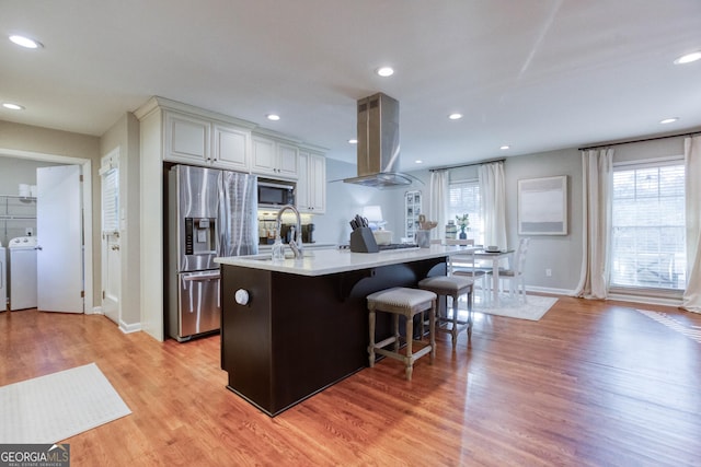 kitchen featuring washer / clothes dryer, appliances with stainless steel finishes, light hardwood / wood-style floors, and ventilation hood