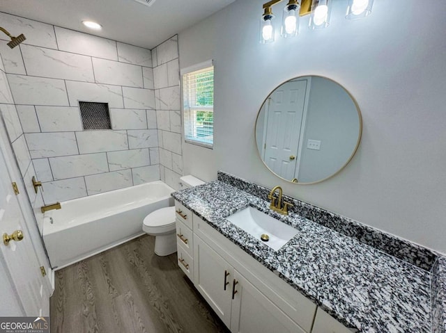 full bathroom featuring vanity, tiled shower / bath, wood-type flooring, and toilet