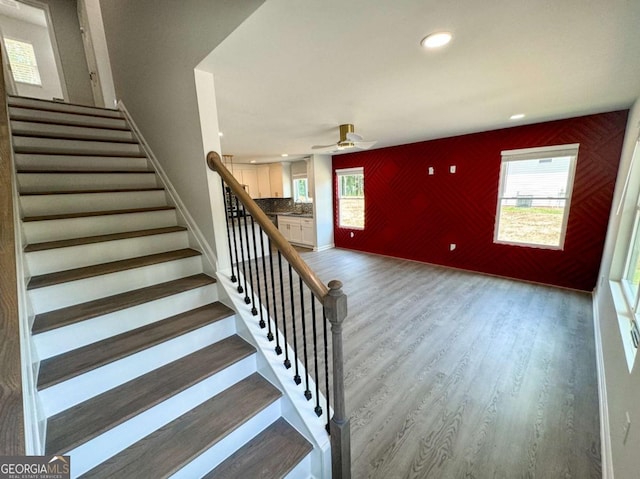 stairs featuring ceiling fan, hardwood / wood-style floors, and a healthy amount of sunlight