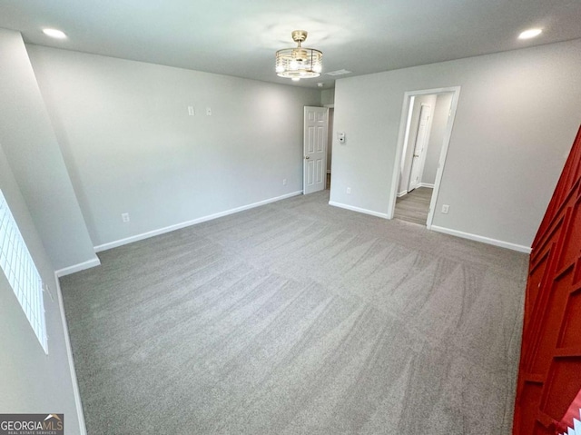 carpeted empty room featuring a notable chandelier