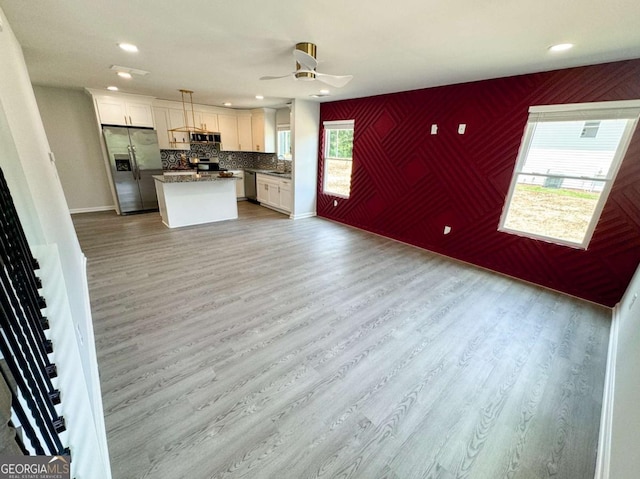 kitchen with white cabinetry, a kitchen island, hanging light fixtures, and appliances with stainless steel finishes