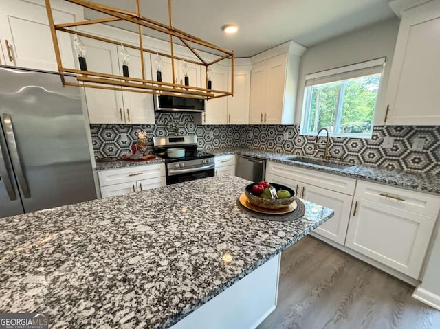 kitchen featuring decorative backsplash, dark stone counters, stainless steel appliances, sink, and white cabinetry