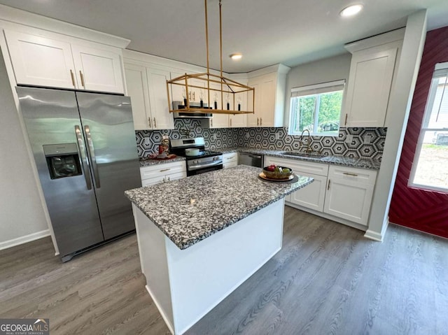 kitchen featuring appliances with stainless steel finishes, white cabinetry, a kitchen island, and sink