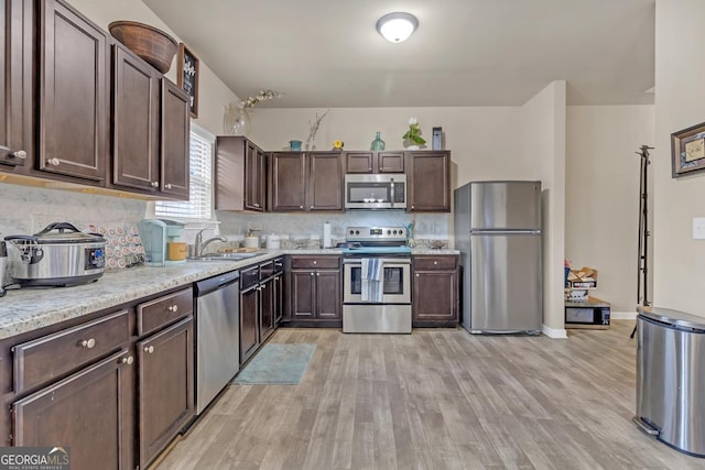 kitchen with dark brown cabinetry, light hardwood / wood-style flooring, stainless steel appliances, and sink