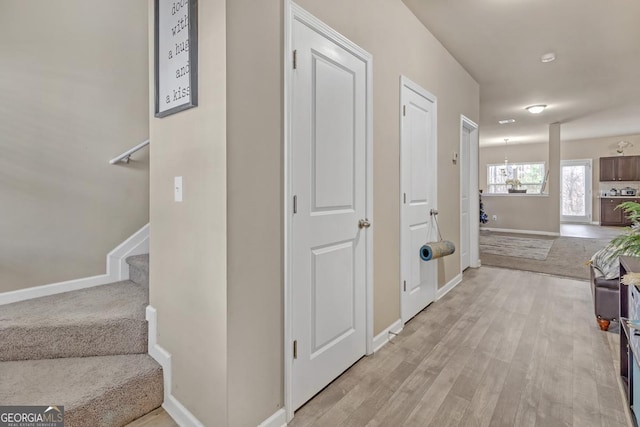 hall with light wood-type flooring and an inviting chandelier