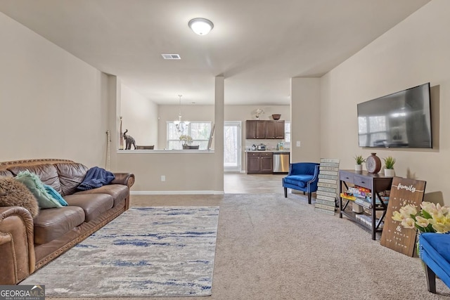 living room featuring light carpet and a notable chandelier