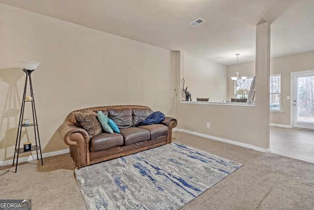 carpeted living room featuring an inviting chandelier