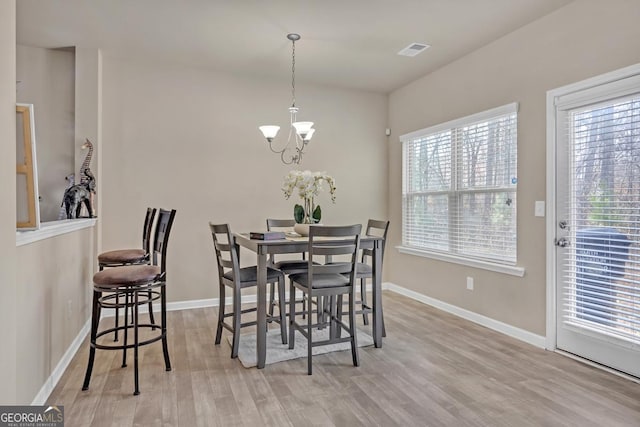 dining room featuring a notable chandelier, light hardwood / wood-style floors, and a wealth of natural light