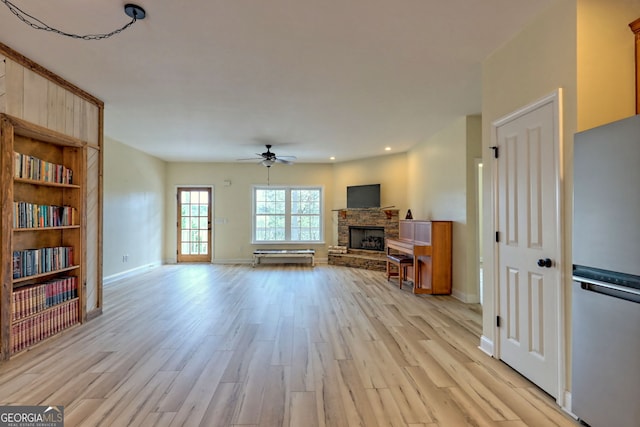 living room featuring a stone fireplace, ceiling fan, and light wood-type flooring