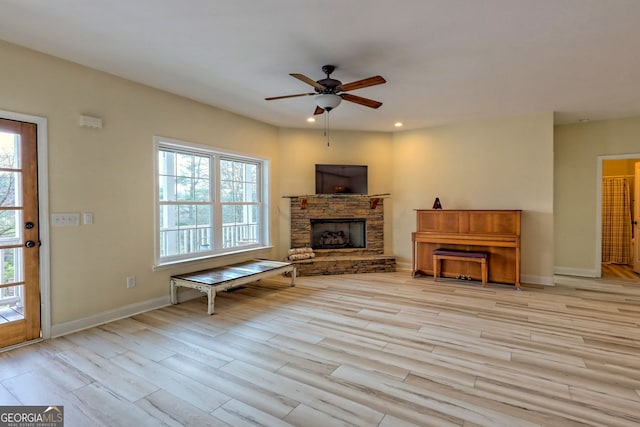 unfurnished living room featuring a stone fireplace, ceiling fan, and light hardwood / wood-style flooring