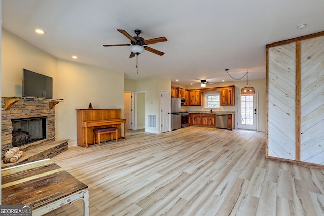 unfurnished living room with a fireplace, light hardwood / wood-style flooring, ceiling fan, and sink